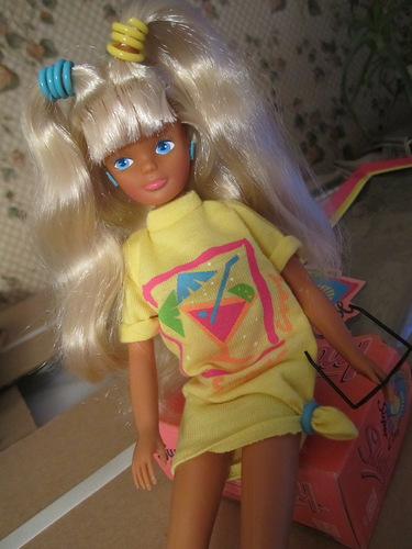 tanned doll dressed in neon, with blonde nylon hair and unnaturally blue eyes